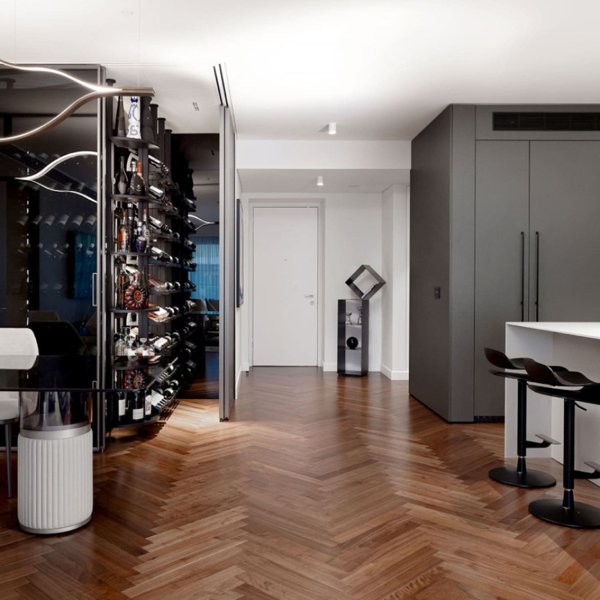 Vitrine cave à vin vitrée et climatisée dans une salle à manger avec cuisine ouverte dans un appartement de luxe. Rangement vin modulable en métal Modulo-X EuroCave