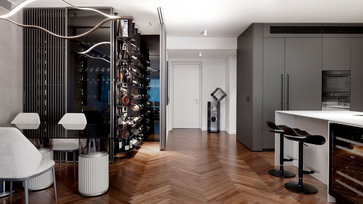 Vitrine de cave à vin climatisée en verre intégrée dans une salle à manger avec cuisine ouverte