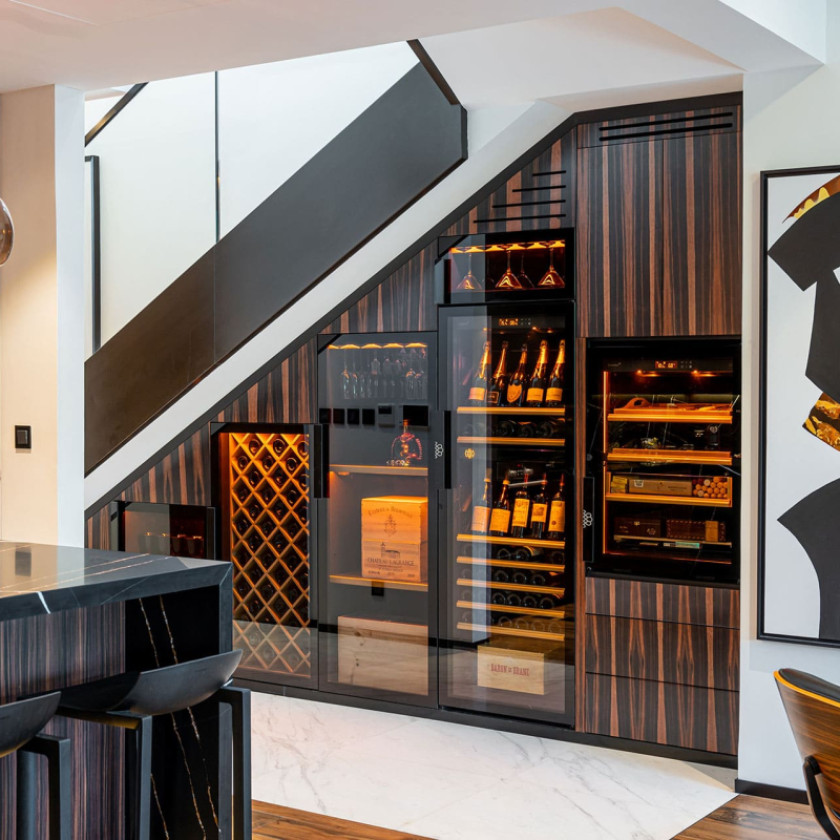 Espace de dégustation privé avec armoires à vin et cigares EuroCave intégrées sous un escalier.